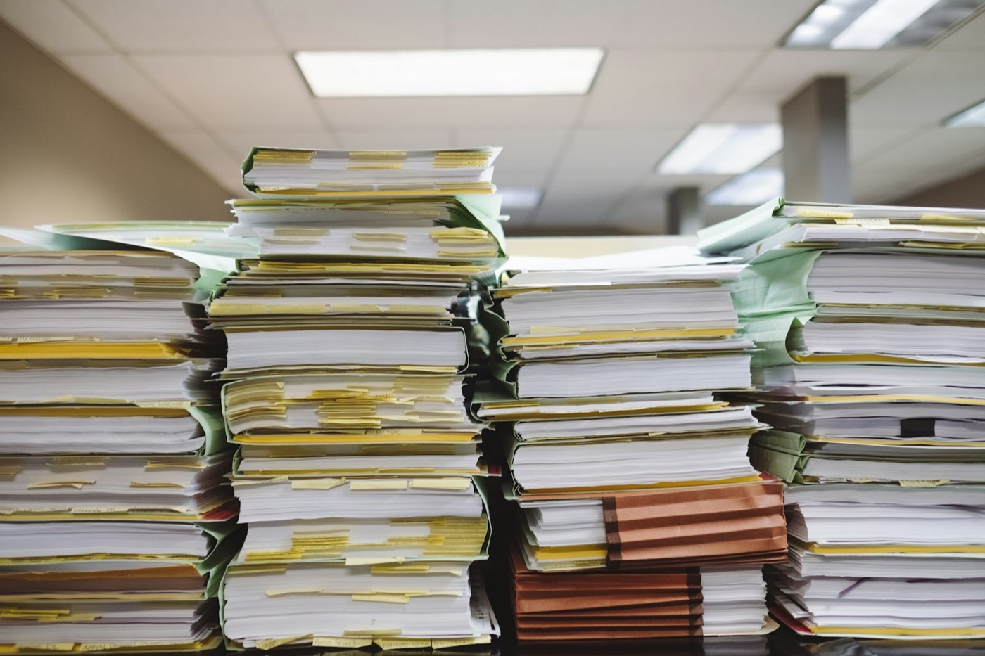 Piles de dossiers et de documents papier dans un bureau